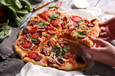 İtalyan mutfağı. Ahşap arka planda sosisli pizza, arka plan resmi, fotokopi alanı, elleri olan pizza.