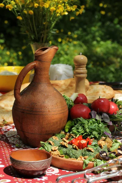 Georgian cuisine. Georgian concept, clay pottery in nature. Lunch with herbs, fresh vegetables and national dishes