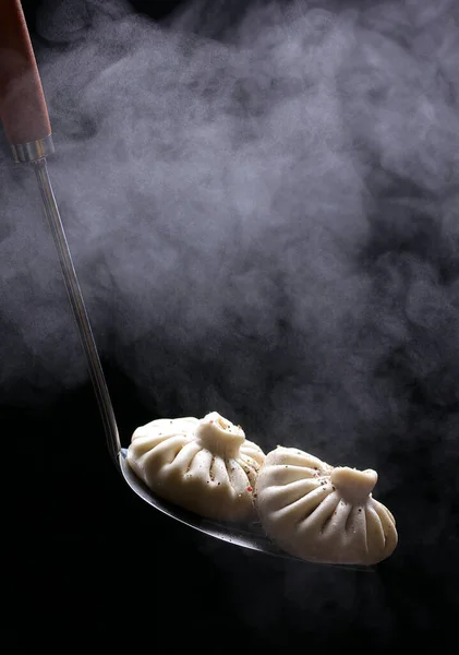 National Georgian cuisine. Khinkali on a black background. Georgian food. Copy space, background image. The steam from the food
