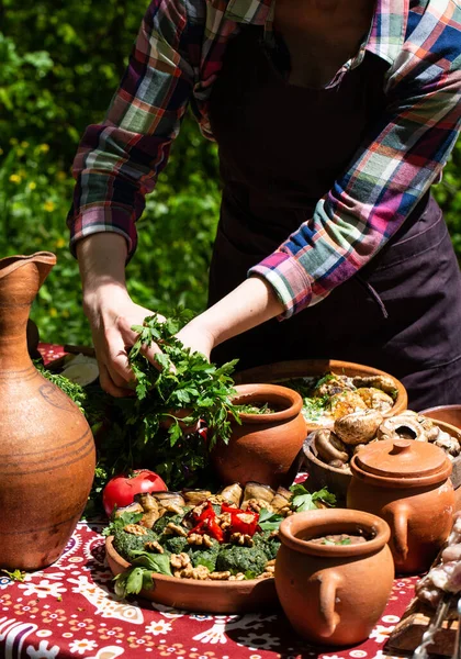 Georgian cuisine. Georgian concept, clay pottery in nature. Lunch with herbs, fresh vegetables and national dishes with hands