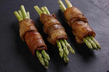 Siyah arka planda siyah tahtada kızarmış pastırma ve kuşkonmaz. - Yakın çekim. Arkaplan resmi, alanı kopyala