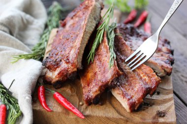 Kızarmış domuz pirzolası, baharatlı, biberiyeli, maydanozlu ve kırmızı biberli kahverengi ahşap arka planda, çatallı ahşap bir tahtada. Taşralı. Et ızgarada. Arkaplan resmi, alanı kopyala