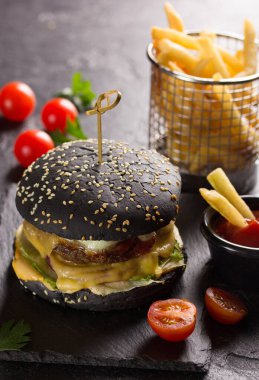 Amerikan gıda konsepti. Esmer arka planda otlu burger, domates ve sığır eti. Ketçaplı patates. Arkaplan resmi, alanı kopyala