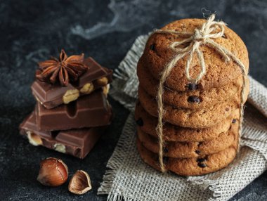 Koyu arkaplanda çikolata ve fındıklı yulaf kurabiyesi. Arkaplan resmi, alanı kopyala