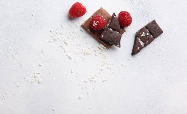 Koyu ve ahududulu sütlü çikolata, hafif arkaplanda hindistan cevizi talaşı. Arkaplan resmi, alanı kopyala