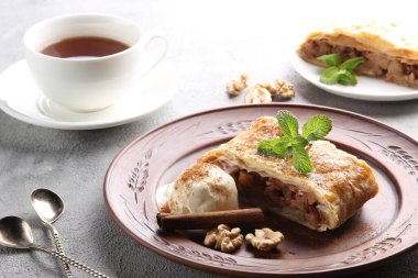 Alman mutfağı kavramı. Tarçınlı elmalı turta, fındıklı dondurma ve arka planda bir fincan çay. Arkaplan resmi, alanı kopyala