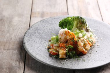 Deniz ürünleri mutfağı. Brokolili, peynirli, cevizli ve gri arka planda otlu karides. Arkaplan resmi, alanı kopyala