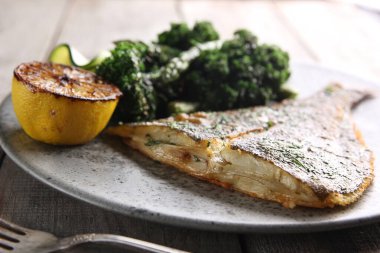 Deniz ürünleri. Hafif ahşap zemin üzerinde kuşkonmaz, limon ve lahana ile kızarmış dil balığı. Sebzeli balık. Arkaplan resmi, alanı kopyala