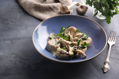 Mantarlı boğa yumurtaları ve krema soslu maydanoz koyu gri arka planda mavi bir kasede. Arkaplan resmi, alanı kopyala