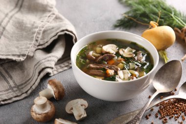 Rus mutfağı kavramı. Mantarlı çorba ve şalgam. Açık arkaplanda yeşillikler, kaşıklar ve karabuğday var. Arkaplan resmi, alanı kopyala