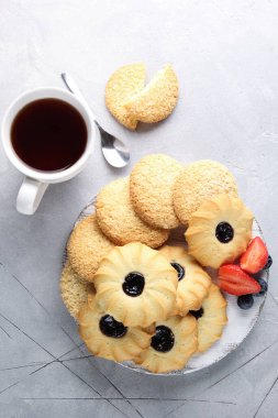 Tatlı. Çaya karşılık şeker. Reçelli kurabiyeler, bir fincan çay ve arka planda taze böğürtlen. Arkaplan resmi, alanı kopyala