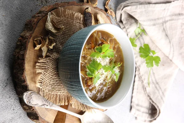 Concept of Russian cuisine. Cabbage soup with mushrooms and herbs. Soup in a bowl with a spoon on a wooden background. Background image, copy space