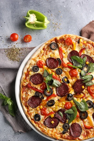 The concept of Italian cuisine. Pepperoni pizza with sausage, salami, tomatoes and olives on a light background. Background image, copy space
