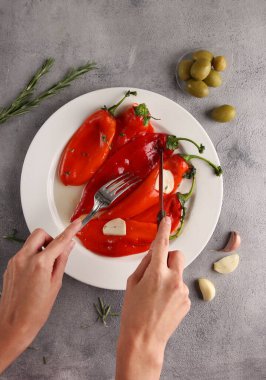 Baharatlı kırmızı biber ve beyaz tabakta elleri olan sarımsak. Biberiye, açık gri arka planda zeytin ve çatal. Arkaplan resmi, alanı kopyala