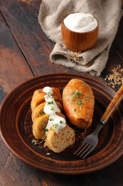 Doğu Avrupa mutfağı kavramı. Etle doldurulmuş lahana, pirinç ve ekşi krema koyu ahşap bir arka planda kahverengi bir tabakta. Taşralı. Arkaplan resmi, alanı kopyala