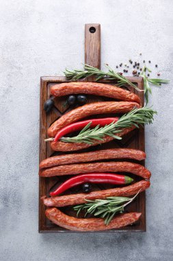 Alman mutfağı kavramı. Biberiyeli tütsülenmiş sosis, gri arka planda ahşap bir tahtada zeytin ve baharatlar. Arkaplan resmi, alanı kopyala