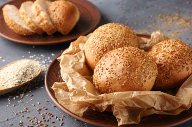 Fırın. Kahverengi tabakta parşömen üzerine susam tohumlu ekmek. Ekmek dilimleri tabağa yakın duruyor. Açık gri bir arkaplanda. Arkaplan resmi, alanı kopyala