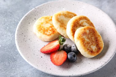 Rus ve Ukrayna mutfağı kavramı. Süzme peynirli krep. Açık gri arka planda taze böğürtlenli cheesecake. Arkaplan resmi, alanı kopyala