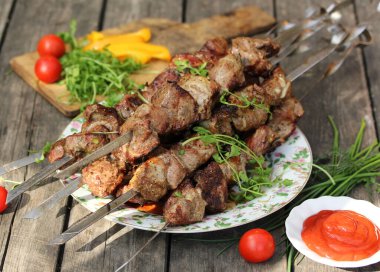 Kavanozda ketçap, domates, biber ve şifalı bitkiler olan eski bir ahşap arka planda hafif bir tabakta ızgara domuz şiş kebabı. Arkaplan resmi, alanı kopyala