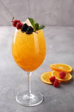 İçkiler. Açık gri arka planda taze böğürtlen, nane ve buzlu bir bardakta portakal kokteyli. Bar menüsü. Arkaplan resmi, alanı kopyala