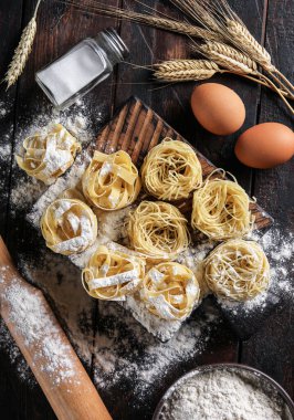 İtalyan mutfağı kavramı. Kuru makarna fettucine ve un, yumurta, merdane ve tuzlu capellini. Eski ahşap bir arka planda çavdar kulakları. Arkaplan resmi