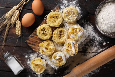 İtalyan mutfağı kavramı. Kuru makarna fettucine ve un, yumurta, merdane ve tuzlu capellini. Eski ahşap arka planda buğday kulakları. Arkaplan resmi