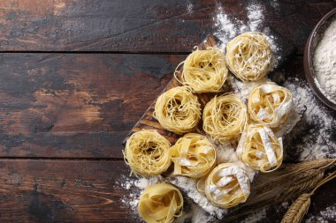 İtalyan mutfağı kavramı. Kuru makarna fettucine ve capellini ile un, yumurta ve buğday kulaklı eski ahşap arka planda. Arkaplan resmi, alanı kopyala
