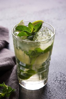 Alkolik Mojito kokteyli, limon, buz ve gri arka planda bir bardakta nane şekeri. Bar menüsü. Yeşil içecek. Arkaplan resmi, alanı kopyala