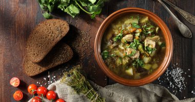 Sebzeli köy çorbası, et ve eski ahşap arka planda kil kasede taze otlar. Ekmek, kimyon, kişniş, domates, kaşık ve biraz da dereotu. Flatlay. Arkaplan resmi, alanı kopyala 