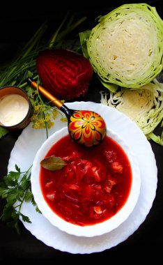 Rus ve Ukrayna mutfağı. Pancar kökü, lahana, ekşi krema ve beyaz tabakta bitkiler. Khokhloma kaşığı. Pancar çorbası. Flatlay. Boşluğu kopyala, üst görünüm