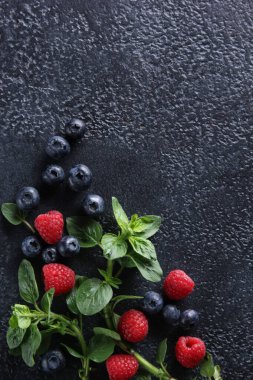 Taze böğürtlen: siyah arka planda yabanmersini, ahududu ve taze nane. Flatlay, üst manzara. Arkaplan resmi, alanı kopyala 