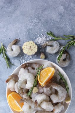Deniz ürünleri. Çiğ yeşil kraliyet karidesleri beyaz tabakta karides, biberiye, limon, sarımsak ve tuz açık gri arka planda. Flatlay, üst manzara. Arkaplan resmi, alanı kopyala 