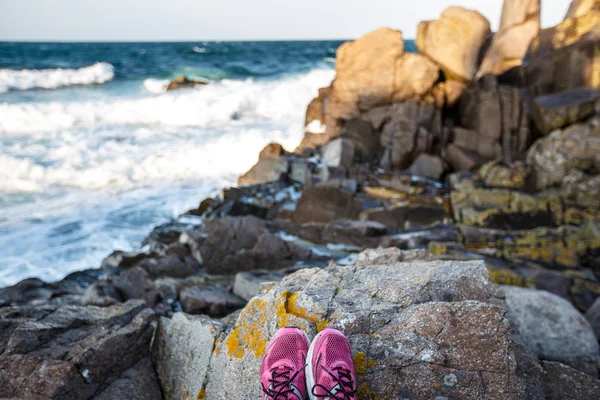 Rocky beach rocks with purple sneakers — Stock Photo, Image