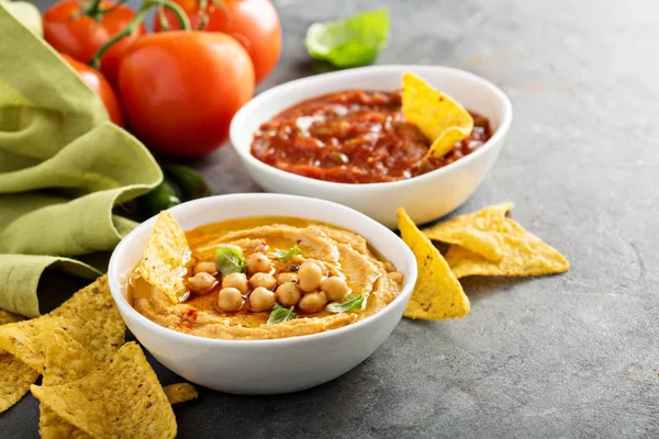 Hummus e salsa di pomodoro fatti in casa in ciotole bianche con patatine fritte — Foto Stock