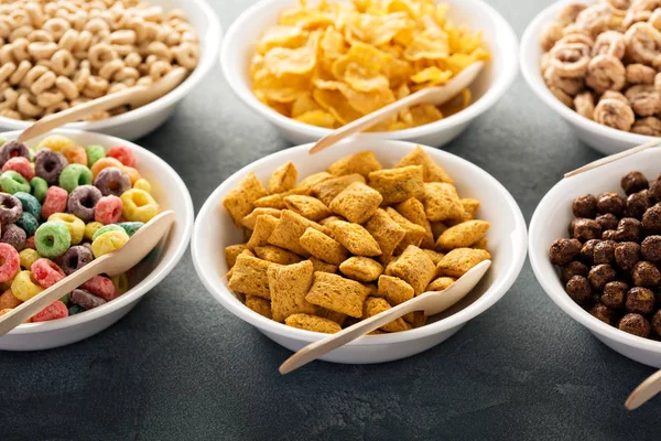 Varietà di cereali freddi in ciotole bianche con cucchiai — Foto Stock