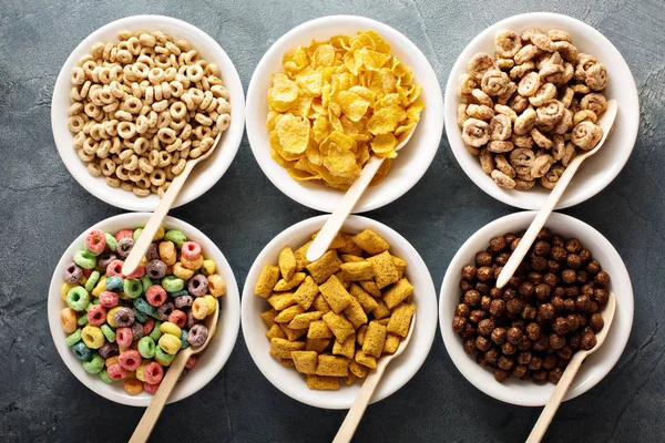 Varietà di cereali freddi in ciotole bianche con cucchiai — Foto Stock