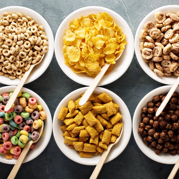 Varietà di cereali freddi in ciotole bianche con cucchiai — Foto Stock