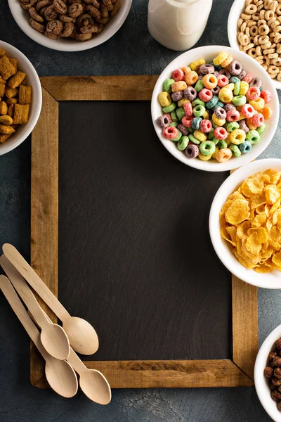 Variety of cold cereals in white bowls around chalkboard — Stock Photo, Image