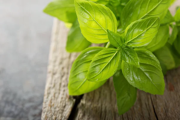 Hojas de albahaca verde fresca sobre una tabla rústica — Foto de Stock