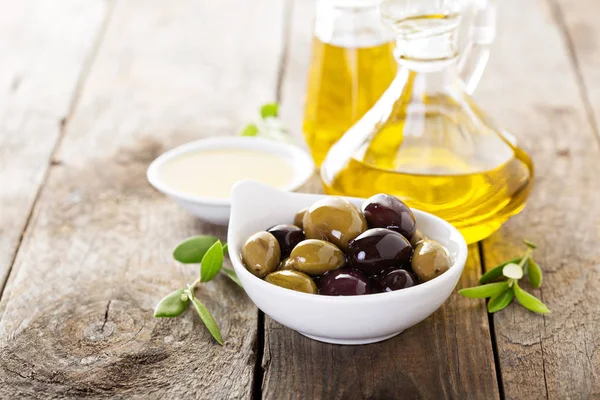 Olio in bottiglia e una ciotola con olive — Foto Stock