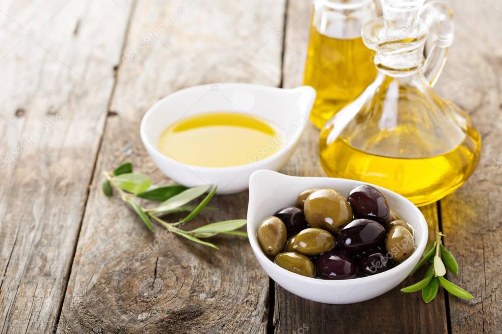 Olive oil in bottles and a bowl with olives