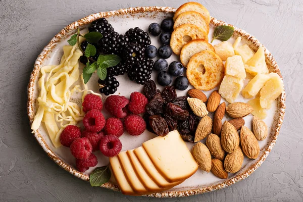 Cheese plate with nuts and berries — Stock Photo, Image