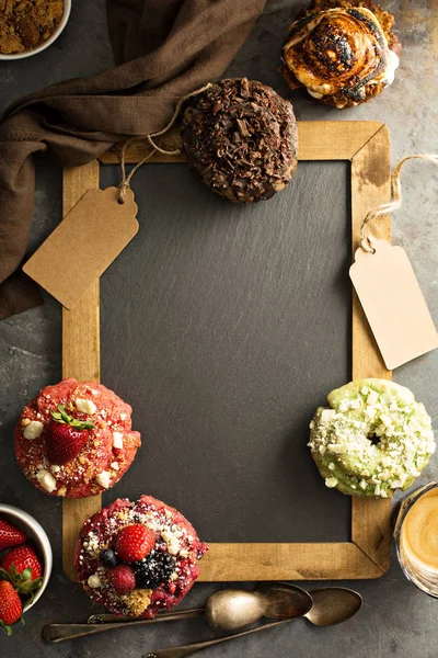 Variety of donuts around a chalkboard — Stock Photo, Image