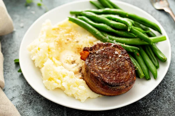 Repas traditionnel avec un steak au bacon et pommes de terre — Photo