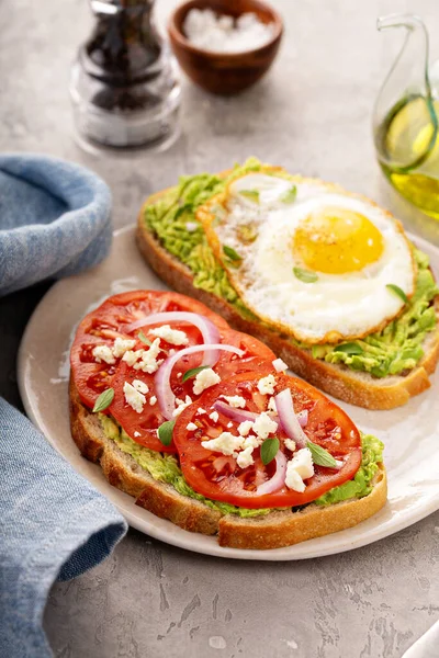 Tostadas de aguacate con huevo frito y tomates de reliquia — Foto de Stock