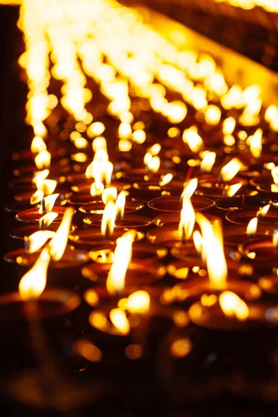 Muchas llamas de velas brillando en la oscuridad — Foto de Stock