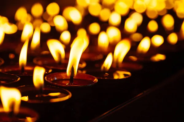 Muchas llamas de velas brillando en la oscuridad — Foto de Stock