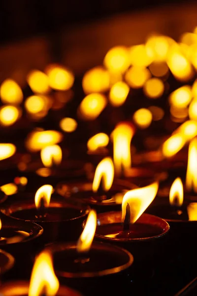 Muchas llamas de velas brillando en la oscuridad — Foto de Stock