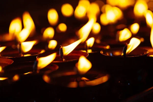 Molte fiamme di candele brillano al buio Foto Stock