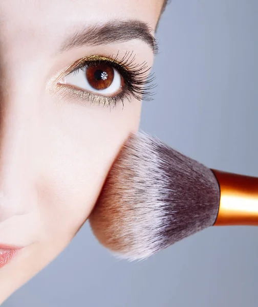 Face of young woman getting powder on her cheek with a brush. — Stock Photo, Image